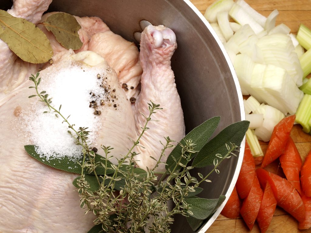 Chicken in a pot for poaching with herbs and vegetables